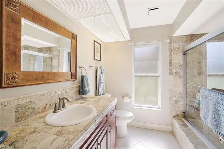 Bathroom featuring light tile patterned flooring, vanity, and tiled shower