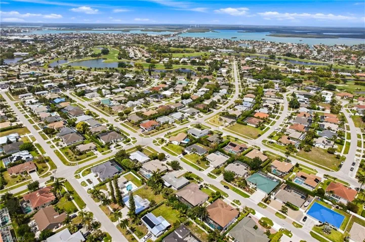 An aerial view of the property's neighborhood, showcasing residential streets, mature trees, and nearby gulfront homes.