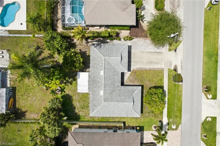 The property features a tile roof, a large concrete driveway with ample parking for guests and plenty of room for a pool or addition.