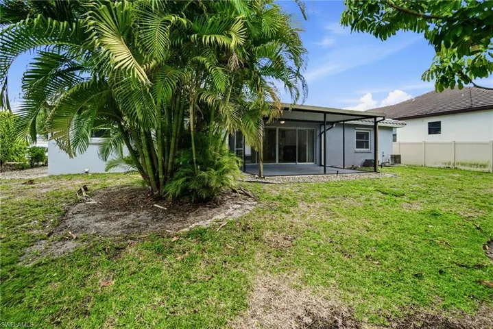 The property includes a spacious backyard, mature palm trees, and a covered patio area with plenty of room for a pool.