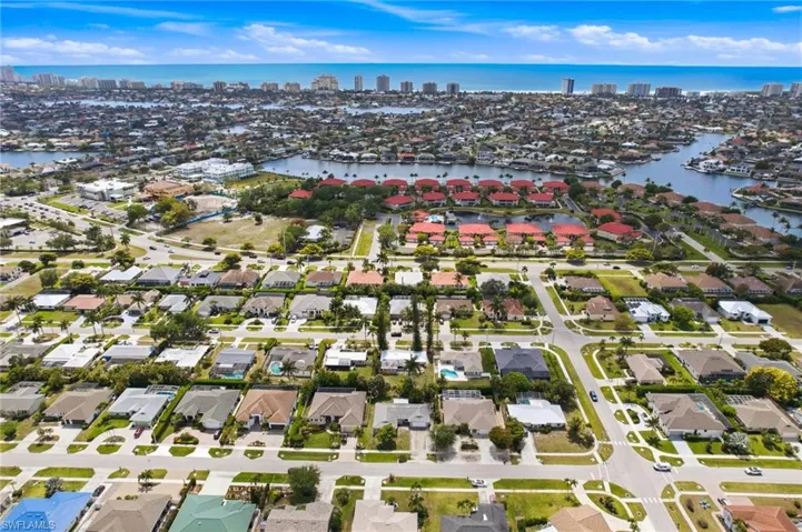 Aerial view showcasing the home on Bermuda Rd with rear southern exposure and waterways and gulfront condos in the distance.