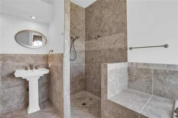 Bathroom with tile floors, tiled shower, and tile walls