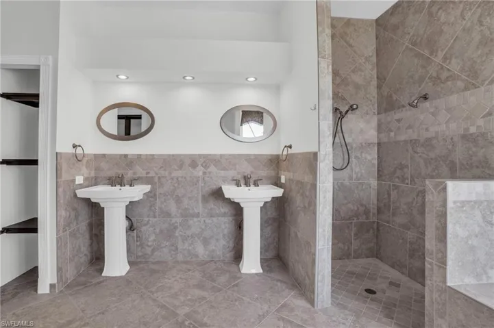 Bathroom featuring a tile shower, tile flooring, and tile walls