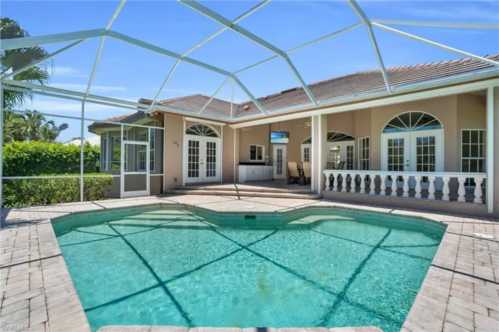 View of pool with french doors, glass enclosure, and a patio area