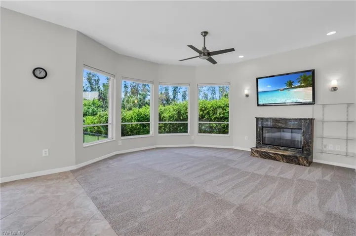 Unfurnished living room featuring a high end fireplace, ceiling fan, and light tile floors