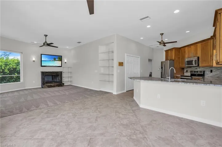 Kitchen with a premium fireplace, appliances with stainless steel finishes, ceiling fan, and tasteful backsplash