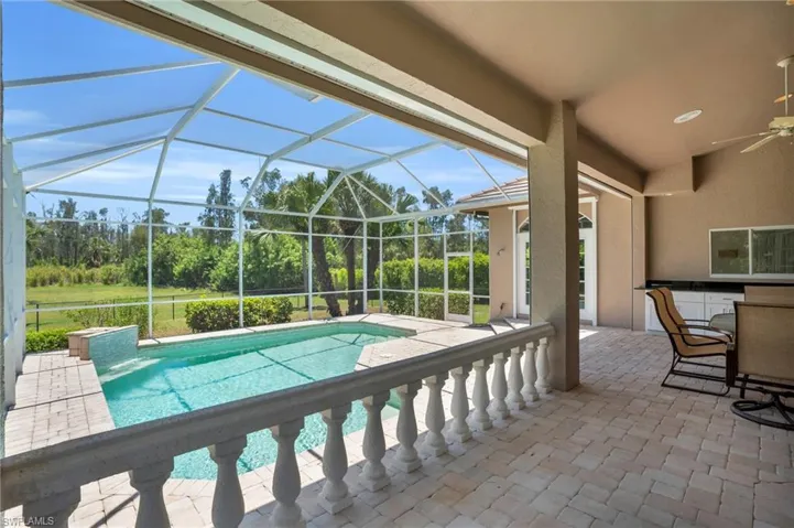 View of swimming pool featuring ceiling fan, glass enclosure, and a patio area