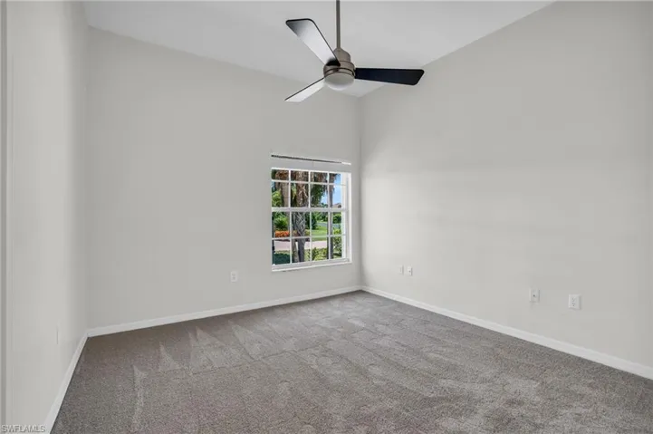 Carpeted empty room featuring high vaulted ceiling and ceiling fan