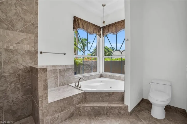 Bathroom featuring tile flooring, tiled tub, and toilet