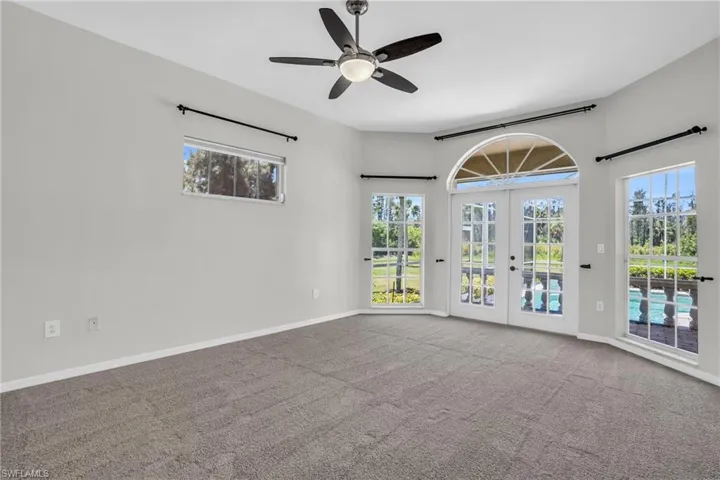 Unfurnished room with a healthy amount of sunlight, french doors, carpet floors, and ceiling fan. Backing to the pool deck.