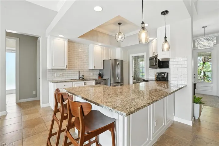 Kitchen featuring appliances with stainless steel finishes, a peninsula, white cabinetry, decorative backsplash, and recessed lighting