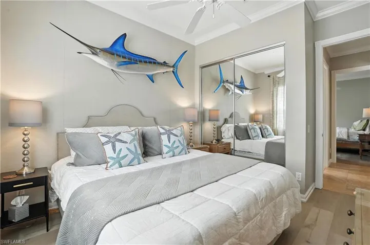 Bedroom with wood finished floors, crown molding, a closet, and a ceiling fan