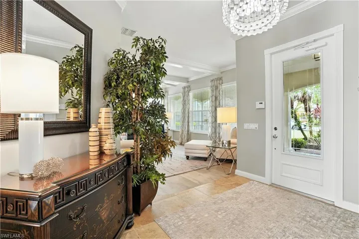 Foyer featuring crown molding, a chandelier, and tile patterned flooring
