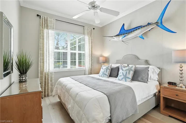 Bedroom featuring light wood-style floors, ornamental molding, and a ceiling fan