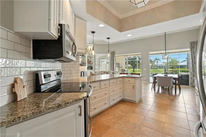 Kitchen featuring stainless steel appliances, crown molding, decorative backsplash, recessed lighting, and a peninsula