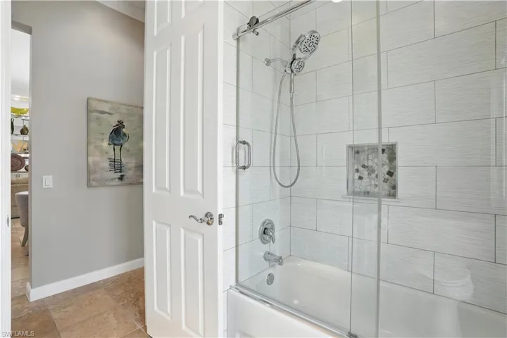 Full bathroom featuring combined bath / shower with glass door and baseboards