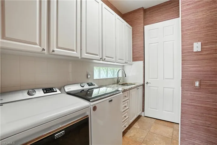 Washroom with separate washer and dryer, cabinet space, and light stone finish floors