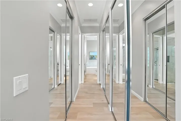 Corridor with crown molding, light wood-type flooring, and recessed lighting