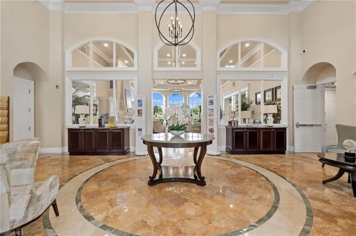Entrance foyer with inlaid floor details, light marble finish flooring, a towering ceiling, crown molding, and arched walkways