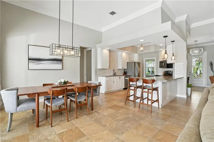 Dining area with ornamental molding, stone tile flooring, and a chandelier