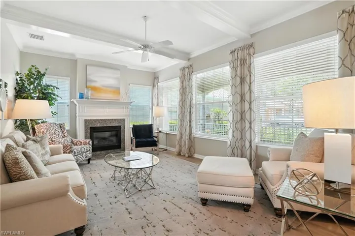 Living area with crown molding, a ceiling fan, a premium fireplace, wood finished floors, and beamed ceiling