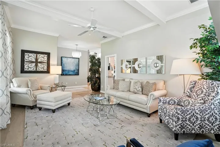 Living room featuring wood finished floors, crown molding, ceiling fan, and beam ceiling