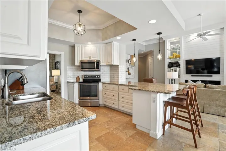 Kitchen with appliances with stainless steel finishes, ornamental molding, a peninsula, tasteful backsplash, and a kitchen breakfast bar