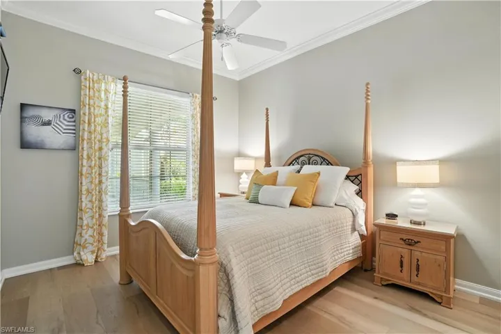 Bedroom featuring crown molding, light wood-type flooring, and a ceiling fan