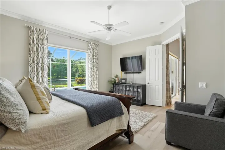 Bedroom with ornamental molding, light wood-style flooring, and a ceiling fan