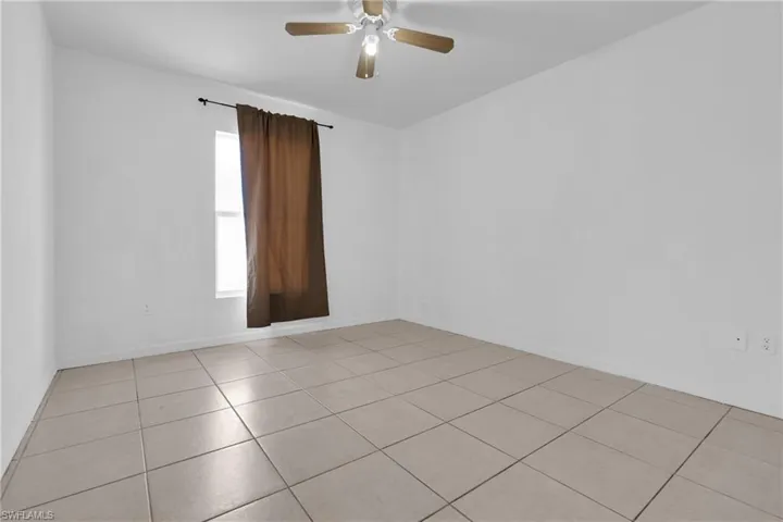 Spacious room featuring neutral tile flooring and white walls
