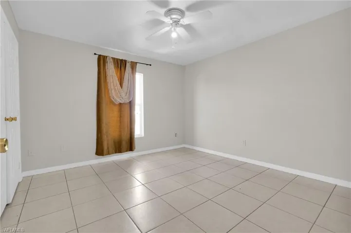 Neutral-toned room featuring light gray walls, large format square tile flooring, and white baseboards
