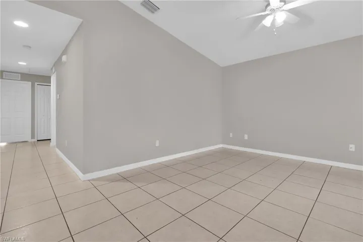 Spacious room featuring vaulted ceilings, light gray wall tones, and large format tile flooring