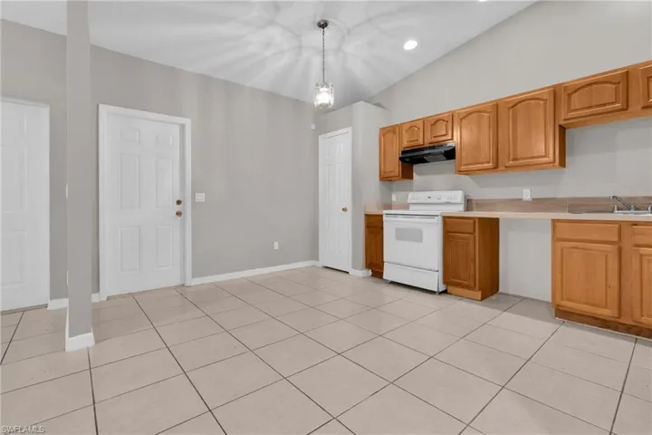 Kitchen space featuring light wood cabinetry, white appliances, and a tile backsplash