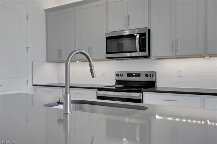 Kitchen with stainless steel appliances, tasteful backsplash, and dark stone counters