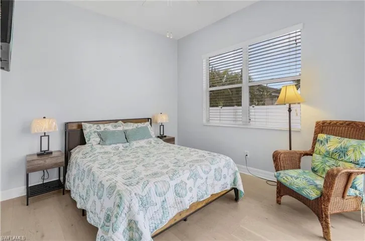 Light wood-finish flooring, a large window with horizontal blinds, and a neutral wall color