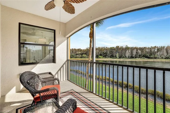 Balcony featuring a water view, a ceiling fan, and view of scattered trees