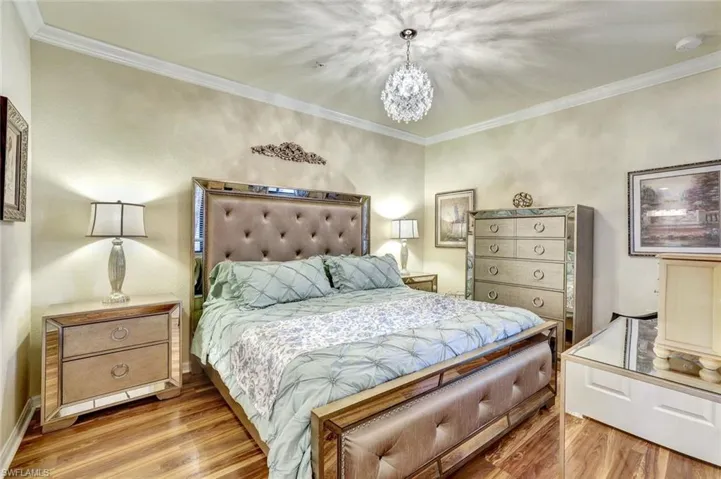 Bedroom with crown molding, wood finished floors, and a chandelier