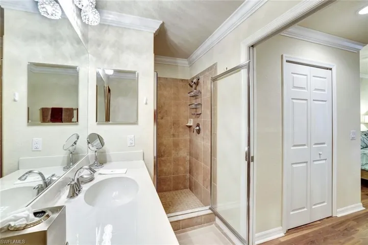 Full bathroom featuring vanity, crown molding, a stall shower, ensuite bath, and light wood finished floors
