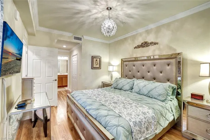 Bedroom featuring ornamental molding, light wood-style floors, a chandelier, a closet, and ensuite bathroom
