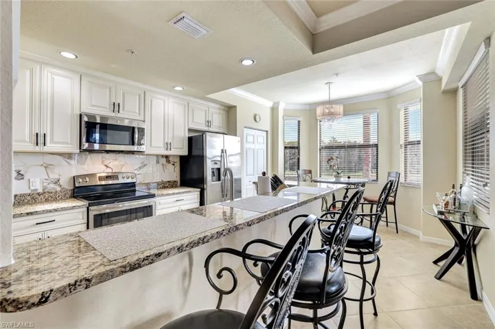 Kitchen featuring stainless steel appliances, light stone countertops, a breakfast bar, tasteful backsplash, and hanging light fixtures