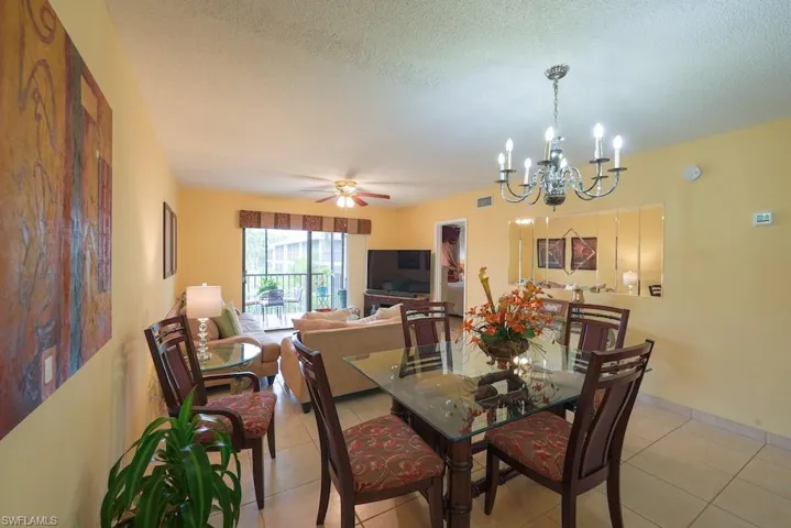 Dining area with light tile patterned floors, a chandelier, ceiling fan, and a textured ceiling