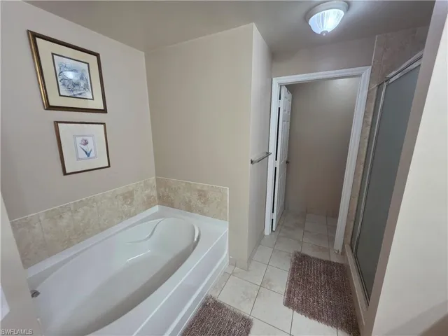 Full bathroom featuring a garden tub, light tile patterned floors, and a stall shower