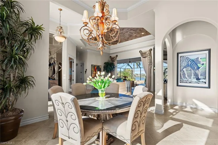 Dining room featuring ornamental molding, a chandelier, tile patterned floors, a high ceiling, and a sunroom