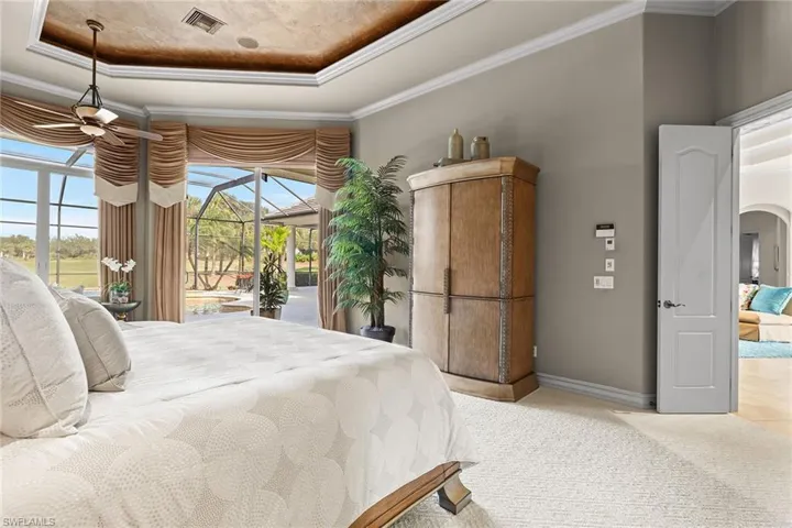 Bedroom featuring a sunroom, crown molding, a tray ceiling, access to outside, and arched walkways