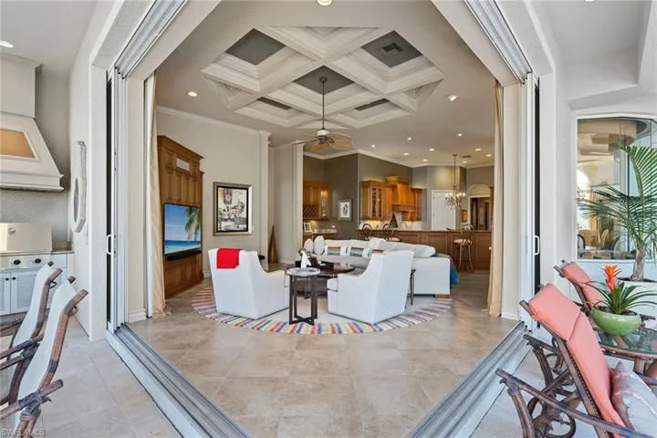 Living area with coffered ceiling, ornamental molding, recessed lighting, and ceiling fan