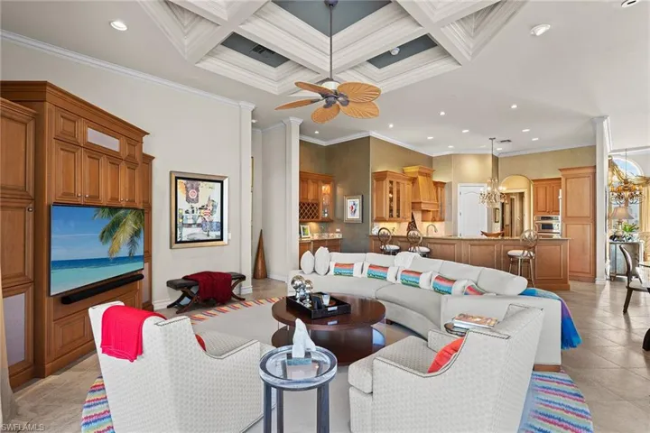 Living room with a towering ceiling, ornamental molding, coffered ceiling, recessed lighting, and light tile patterned floors