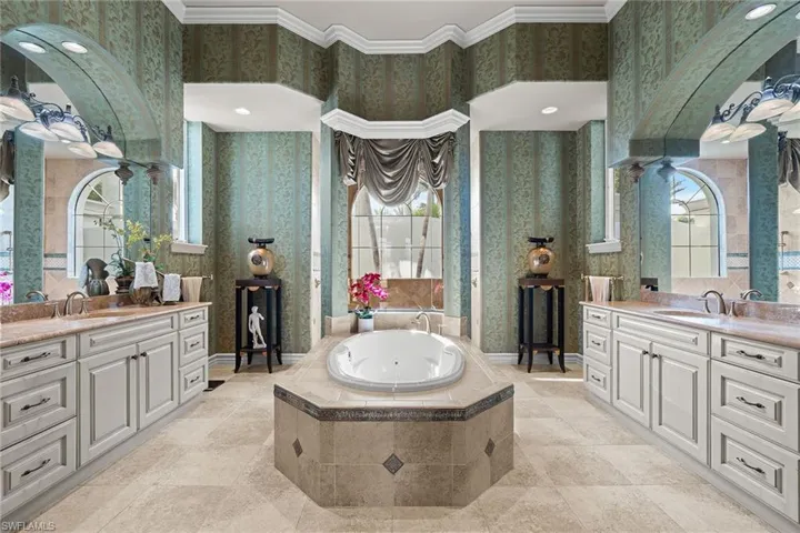 Bathroom featuring crown molding, two vanities, a tub with jets, wallpapered walls, and recessed lighting