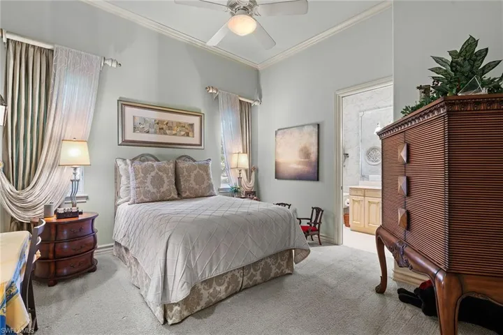 Bedroom with ornamental molding, carpet, ceiling fan, and ensuite bathroom