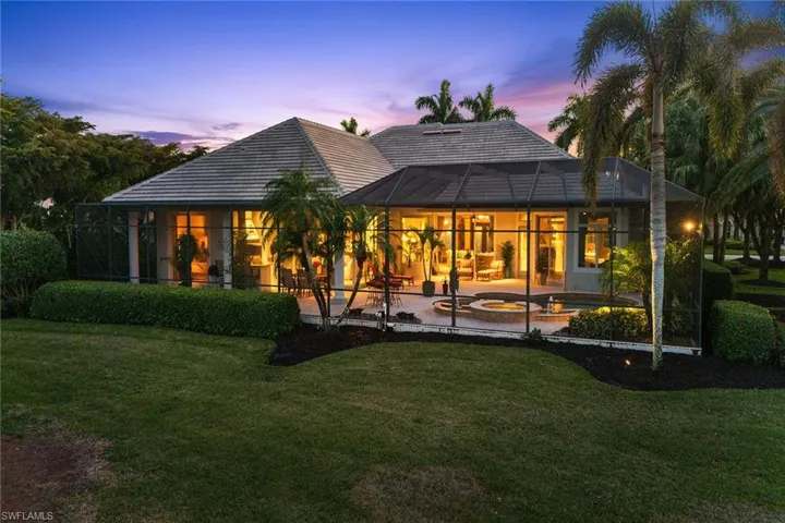 Back of property at dusk with a sunroom, a yard, glass enclosure, and a patio area