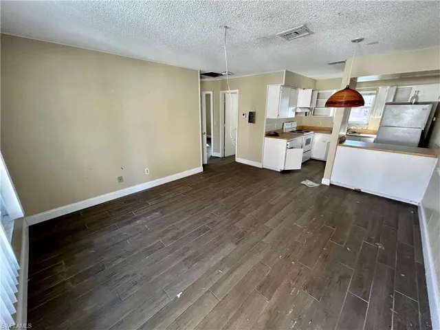 Kitchen featuring pendant lighting, white appliances, white cabinetry, and dark wood-type flooring